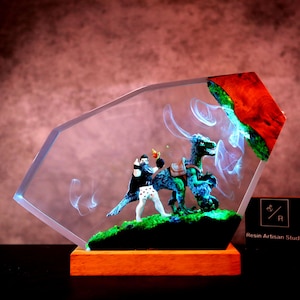 May include: A unique resin art piece featuring a miniature scene with a dinosaur and a figure. The artwork is encased in a clear, geometric block, set on a wooden base. The dinosaur is blue and green, and the figure is wearing a black cape.