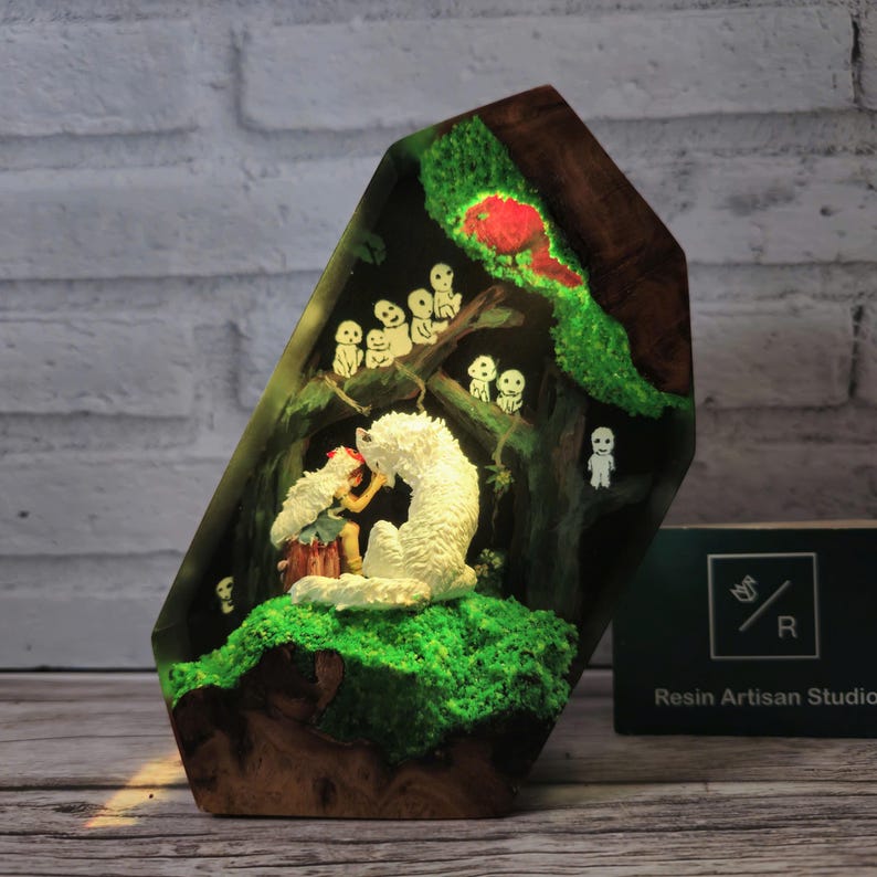May include: A resin sculpture of a white wolf and a small human figure in a forest setting. The wolf is sitting down and the human is standing next to it. The sculpture is lit from behind, creating a glowing effect. The sculpture is set in a wooden base.