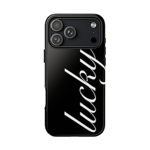 Könnte beinhalten: Schwarze Handyhülle mit dem Wort "lucky" in weißer Schrift. Das Gehäuse hat eine glänzende Oberfläche und ein Kameramodul mit drei Objektiven. Die Hülle ist für ein Smartphone konzipiert.