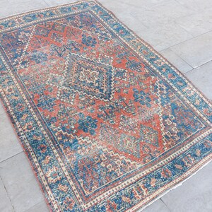 May include: A vintage rug with a blue and red geometric pattern. The rug has a faded, distressed look and is made of wool.