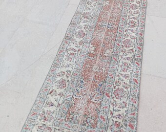 Puede incluir: Una alfombra de pasillo vintage con un centro rojo descolorido y intrincados patrones florales en tonos azules, crema y rosa.