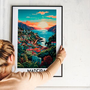 May include: A framed poster with a colorful illustration of a coastal town with a sunset in the background. The text "MADEIRA" is at the bottom of the poster.