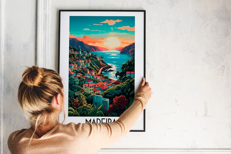 May include: A framed poster with a colorful illustration of a coastal town with a sunset in the background. The text "MADEIRA" is at the bottom of the poster.