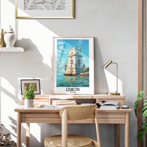 Op de afbeelding: Een ingelijste poster met een kleurrijke illustratie van een toren in het water. De poster heeft de tekst "LISBON, PORTUGAL" onderaan.