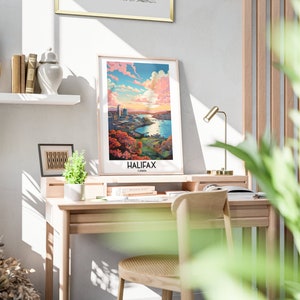 K&ouml;nnte beinhalten: Ein gerahmter Druck einer Stadtlandschaft mit einem Fluss und einem Sonnenuntergangshimmel. Der Druck ist mit "HALIFAX, Kanada" betitelt. Der Druck h&auml;ngt an einer wei&szlig;en Wand &uuml;ber einem Holztisch mit einer Lampe und einem Stuhl.