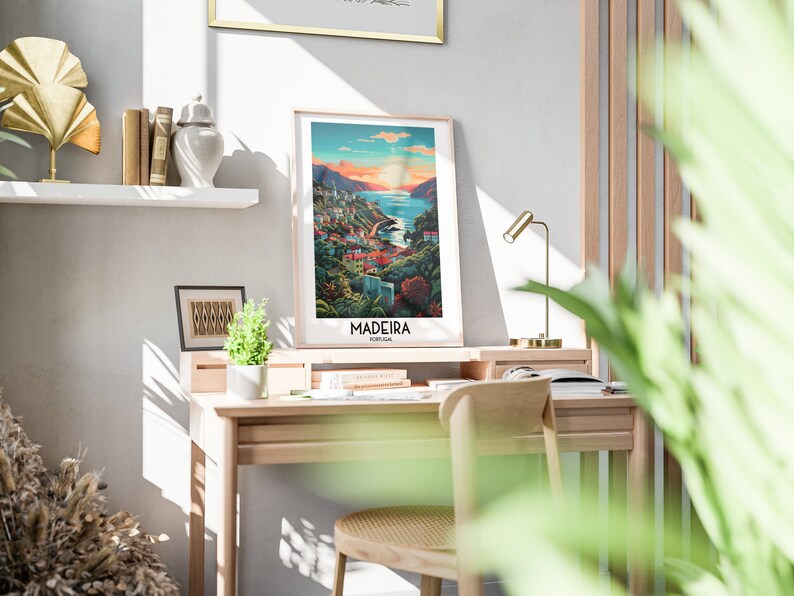 May include: A framed poster with a colorful illustration of a coastal town with a body of water in the background. The poster has the text "Madeira, Portugal" at the bottom.