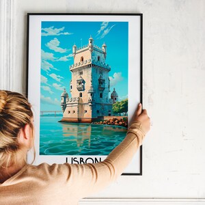Op de afbeelding: Een ingelijste poster met een kleurrijke illustratie van een toren in het water. De poster heeft het woord "LISBON" onderaan gedrukt.