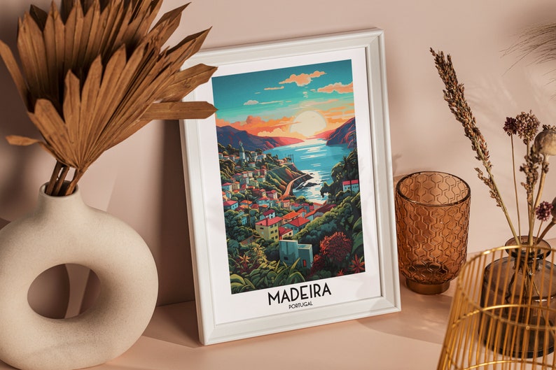 May include: A white framed print with a colorful illustration of a coastal town with a sunset in the background. The text "MADEIRA PORTUGAL" is at the bottom of the print.