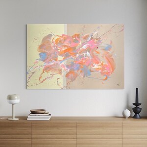 Könnte beinhalten: Abstrakte Malerei mit floralem Thema. Das Kunstwerk zeigt eine Mischung aus rosa, orange und blauen Pinselstrichen auf beigem Hintergrund. Spritzeffekte verleihen dem Stück Textur und Bewegung. Das Gemälde wird über einem Holzschrank ausgestellt.