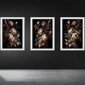 May include: Three framed floral art prints. Each print features a bouquet of flowers in shades of cream, brown, and green against a dark background. The frames are white, and the artwork is displayed on a dark gray wall.