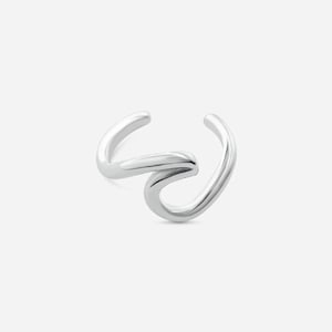 Könnte beinhalten: Ein silberner Ohrklemme mit einem fließenden, wellenartigen Design. Die Klemme umschließt das Ohr und erzeugt einen modernen und minimalistischen Look. Der Schmuck besteht aus glänzendem, reflektierendem Metall.