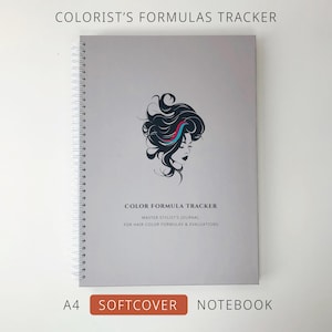 Op de afbeelding: Een grijs A4-notitieboek met zachte kaft getiteld COLORIST'S FORMULAS TRACKER. De kaft bevat een zwarte grafische illustratie van een hoofd met vloeiend haar, geaccentueerd door een rode en blauwe lok, en de tekst COLOR FORMULA TRACKER.