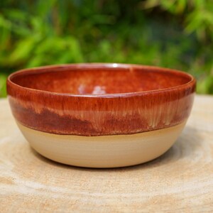 Peut inclure: Un bol en céramique rond présentant un design bicolore avec une glaçure brillante brun-rouge foncé sur la partie supérieure et une finition mate lisse beige clair sur la moitié inférieure, affichant une forme circulaire simple et fonctionnelle.