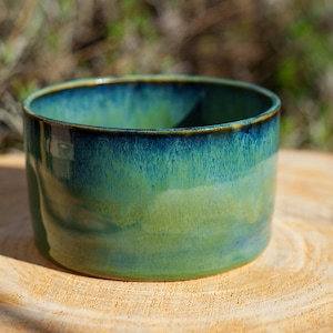 Può includere: Una ciotola in ceramica fatta a mano con finitura lucida. La ciotola presenta una sfumatura di colori, che passa da un verde acqua intenso sul bordo a un verde vibrante sulla base. La ciotola misura circa 10 cm di diametro e 7,6 cm di altezza.
