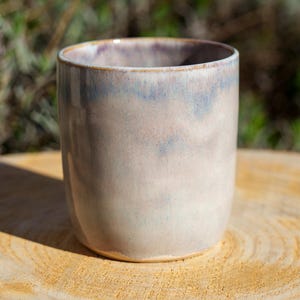 Op de afbeelding: Een set van drie keramische mokken met een gespikkelde, matte afwerking. De mokken zijn in de tinten crème, lichtgrijs en donkergrijs. Elke mok heeft een eenvoudig, minimalistisch ontwerp, perfect voor koffie of thee.