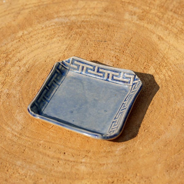 Vierkante Griekse frieskom van blauw keramiek. Sieradenschaaltje van blauw aardewerk. Blauw vierkant sieradenschaaltje. Blauwe, vierkante zaklepel.