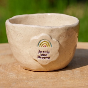 Könnte beinhalten: Eine weiße Keramikschüssel mit einem Regenbogen und dem Text "je suis une licorne" auf Französisch.