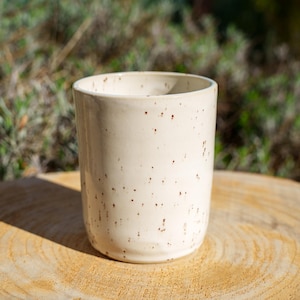 Peut inclure: Ensemble de trois tasses en céramique avec une finition mate et mouchetée. Les tasses sont de couleur crème, grise et noire. Chaque tasse a un design simple et moderne, idéal pour le café ou le thé. Les tasses sont empilées.