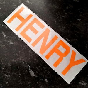 May include: Orange vinyl sticker with the name "HENRY" printed in bold, uppercase letters.