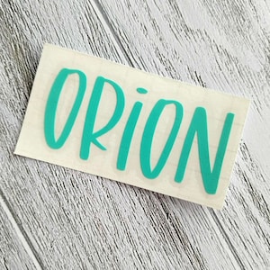 May include: Teal vinyl sticker with the word "ORION" written in a cursive font.
