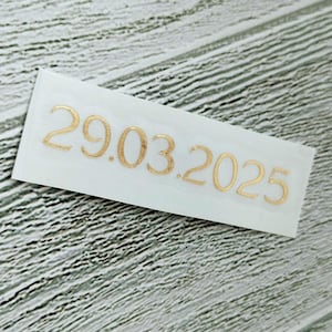 May include: A white sticker with the date 29.03.2025 printed in gold.