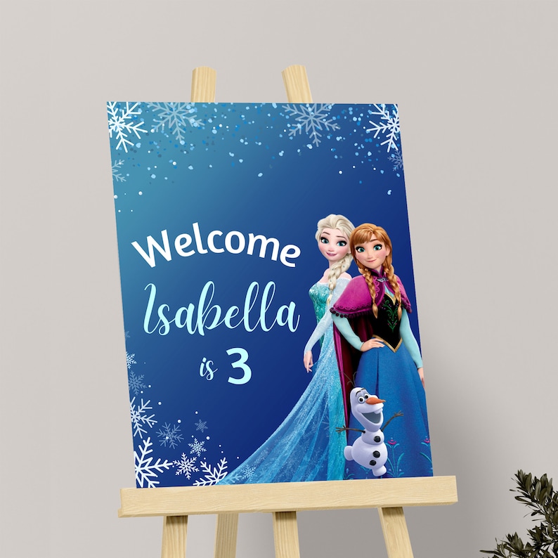 May include: A blue and white welcome sign with a Frozen theme. The sign features Elsa and Anna from the movie Frozen, along with Olaf. The text on the sign reads "Welcome Isabella is 3".