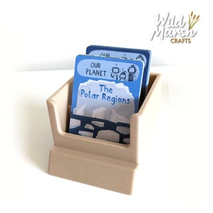 May include: A beige card holder with two blue cards inside. The top card has the text "Our Planet" and the bottom card has the text "The Polar Regions".