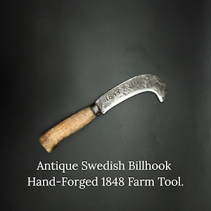 May include: Antique Swedish billhook farm tool, hand-forged in 1848. The curved blade is made of aged metal, and the handle is made of wood. The text "1848 AGID" is visible on the blade.