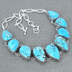 May include: A silver necklace with a turquoise stone pendant. The necklace has a silver chain and a lobster clasp.