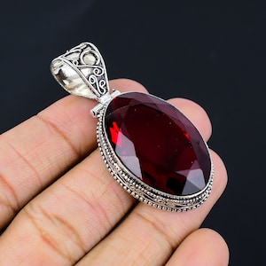 May include: A silver pendant with an oval-shaped red gemstone set in a detailed silver frame.