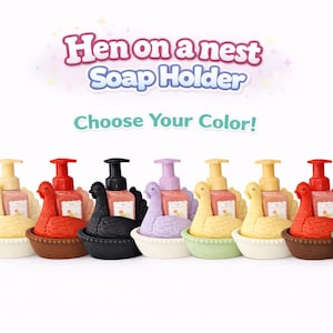 以下が含まれることがあります： ニワトリの巣を模したカラフルなソープディスペンサーのコレクション。各ディスペンサーにはポンプが付いており、ピンク、黄色、赤、黒など様々な色があります。「Hen on a nest Soap Holder」と「Choose Your Color!」の文字が表示されています。