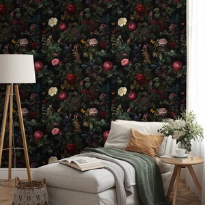 Pu&ograve; includere: Un divano bianco con una coperta verde e un cuscino marrone si trova di fronte a una carta da parati floreale scura con fiori rossi, bianchi e rosa.