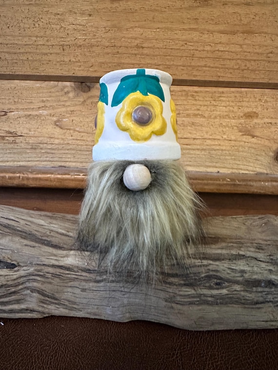 A handmade gnome hiding inside a flower pot — the 'pot head' pun lands perfectly as quirky shelf decor that doubles as a gag gift.