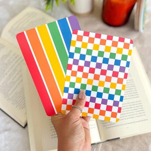 May include: Two rectangular cards with rounded corners. One card features vertical stripes in red, orange, yellow, green, and purple. The second card displays a multi-colored checkerboard pattern consisting of small squares in red, orange, yellow, green, blue, and purple.
