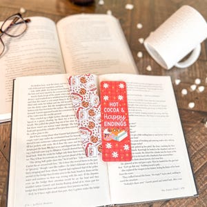 May include: A red and white bookmark with the text "Hot Cocoa & Happy Endings" and a design of cookies, mugs, and snowflakes.