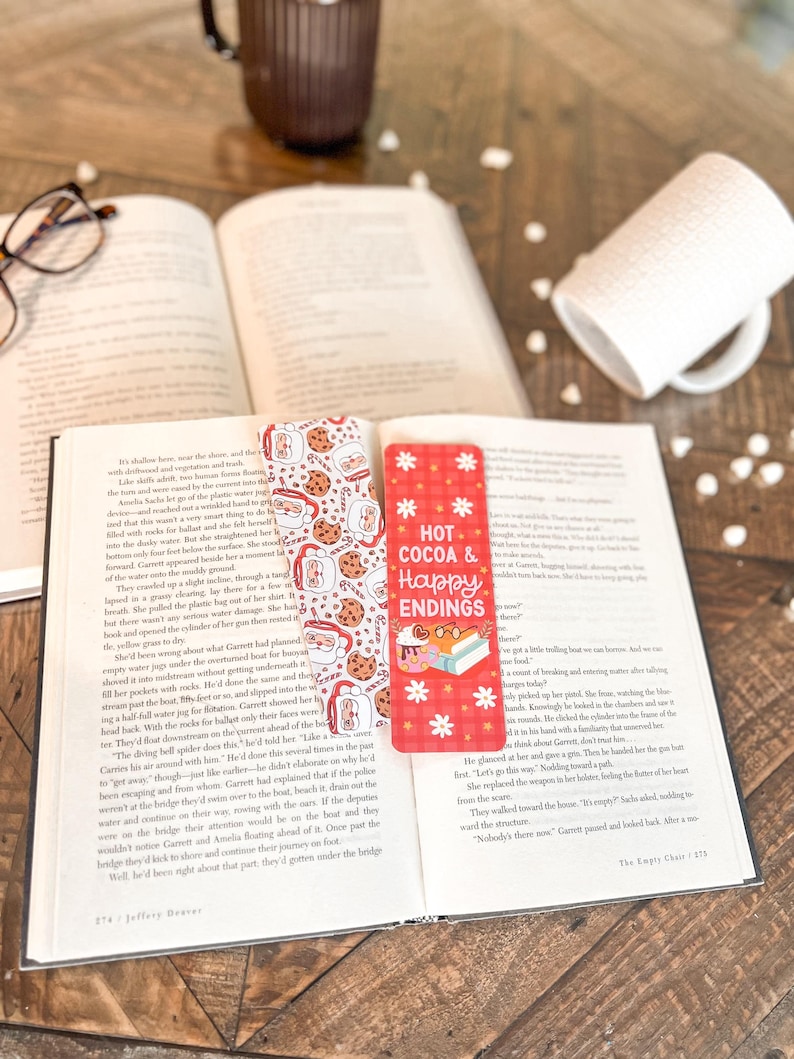 May include: A red and white bookmark with the text "Hot Cocoa & Happy Endings" and a design of cookies, mugs, and snowflakes.