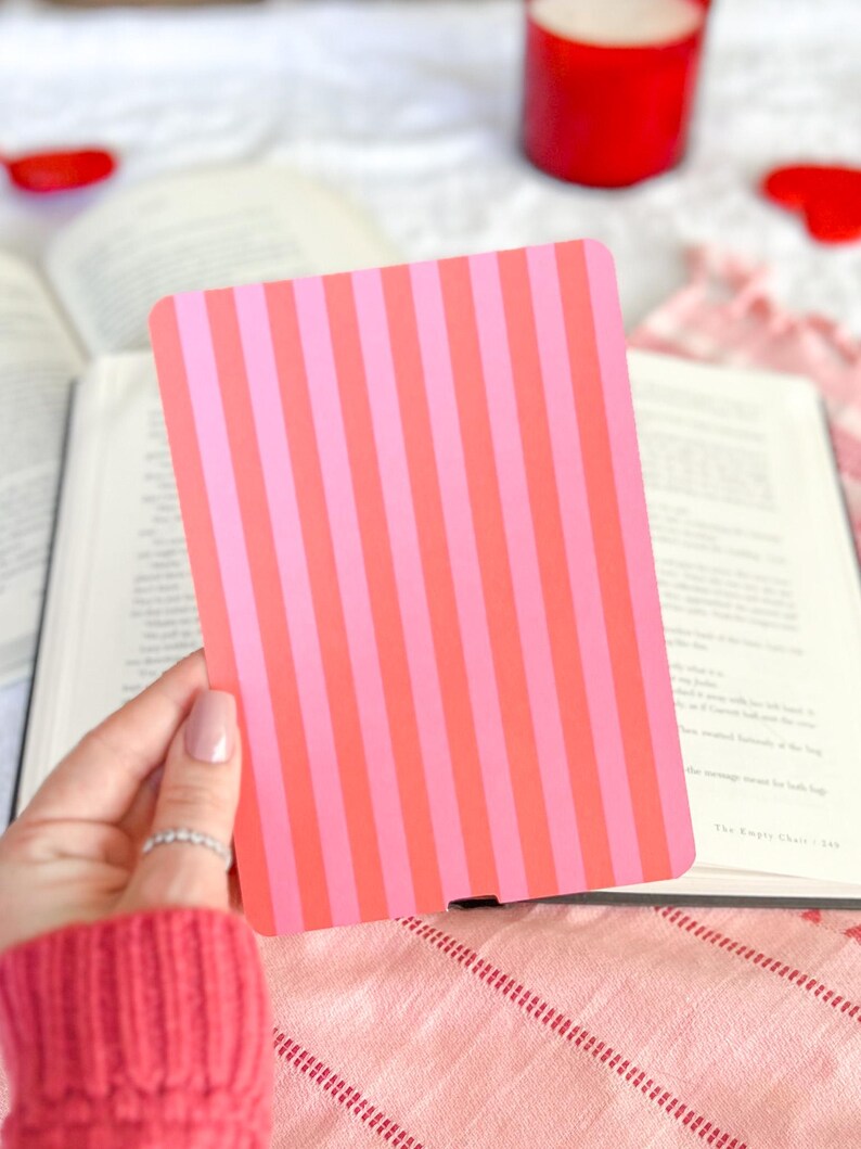 May include: A rectangular card featuring a vertical striped pattern in alternating shades of bright pink and coral orange. The card has rounded corners and a smooth, flat surface, presented as a solid, opaque object with a consistent colour scheme.