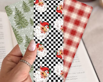 May include: Three rectangular bookmarks featuring distinct patterns: one with green pine trees on a light background, one with a black and white checkerboard print featuring Santa Claus faces, and one with a red and white plaid design.