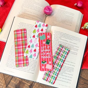 May include: Five colorful Christmas-themed bookmarks with plaid and tree designs. The bookmarks feature the text "Let it snow let me read".