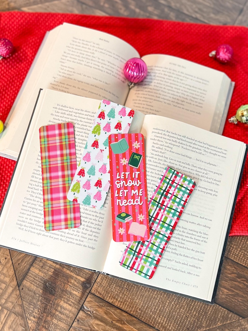 May include: Five colorful Christmas-themed bookmarks with plaid and tree designs. The bookmarks feature the text "Let it snow let me read".