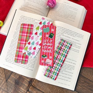 May include: Five Christmas-themed bookmarks with red and green plaid patterns, featuring a variety of designs including a Christmas tree, a book, and the text "Let it snow, Let me read".