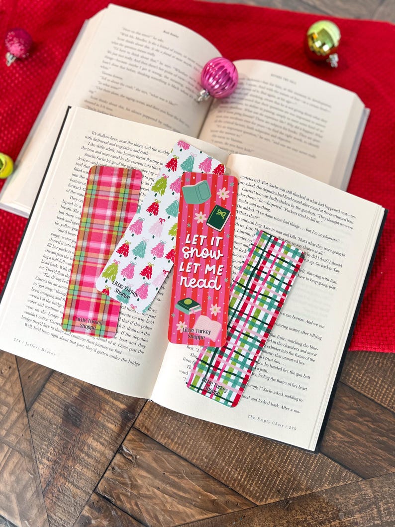May include: Five Christmas-themed bookmarks with red and green plaid patterns, featuring a variety of designs including a Christmas tree, a book, and the text "Let it snow, Let me read".