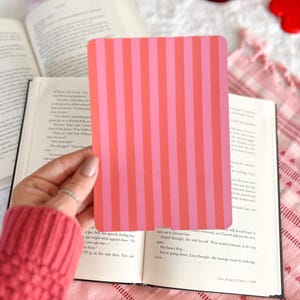 May include: A rectangular card featuring a repeating vertical striped pattern in alternating shades of bright pink and coral orange. The card has rounded corners and a smooth, flat surface, presented as a solid, opaque graphic element.