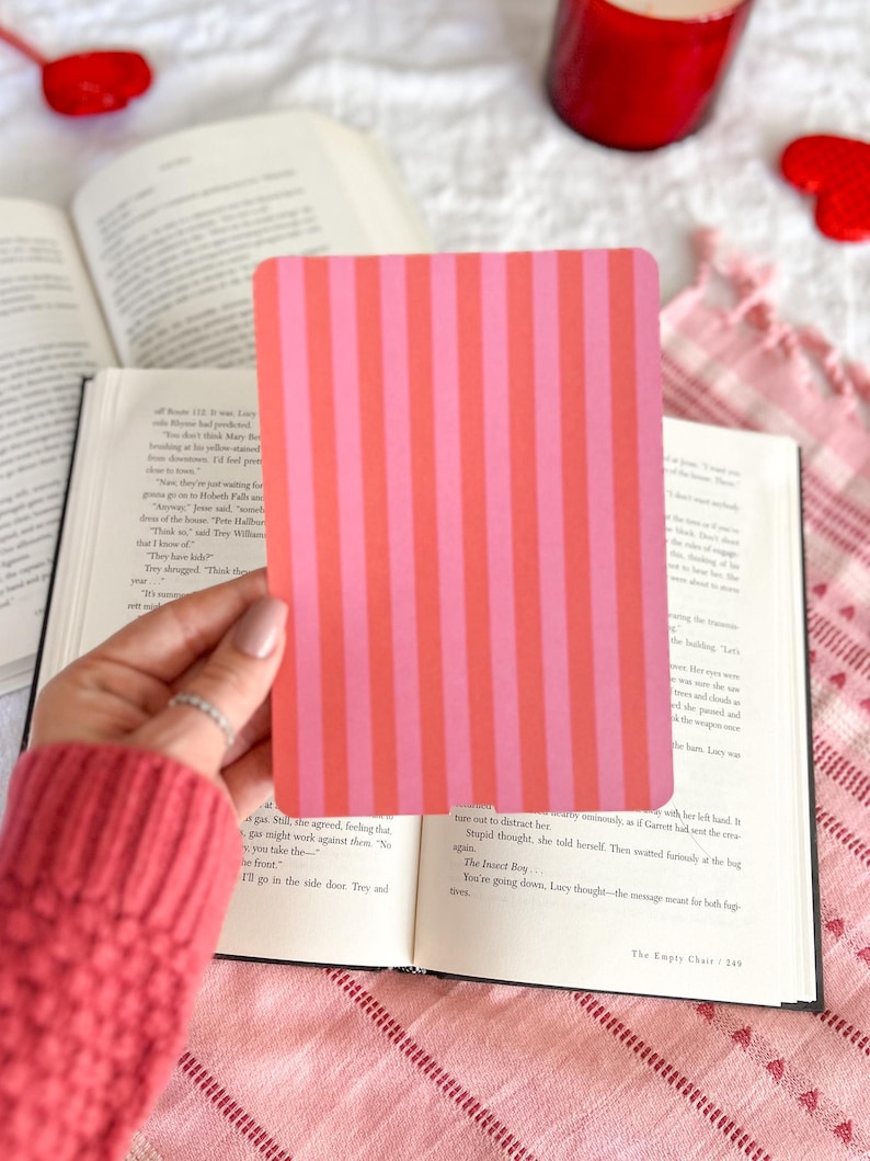 May include: A rectangular card featuring a repeating vertical striped pattern in alternating shades of bright pink and coral orange. The card has rounded corners and a smooth, flat surface, presented as a solid, opaque graphic element.