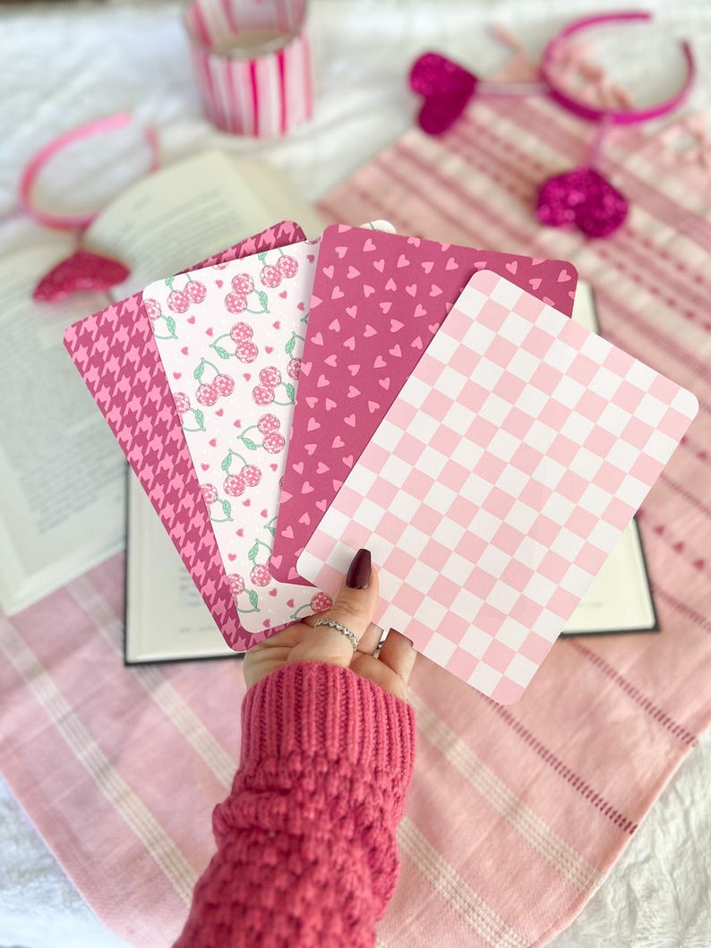 May include: Four pink patterned cards with different designs. The cards feature a checkered pattern, a pattern of small hearts, a pattern of cherries, and a houndstooth pattern.