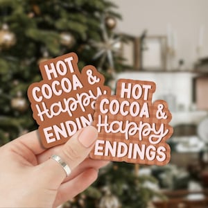 May include: Two brown and pink patterned stickers with the text "Hot Cocoa & Happy Endings" in white lettering.