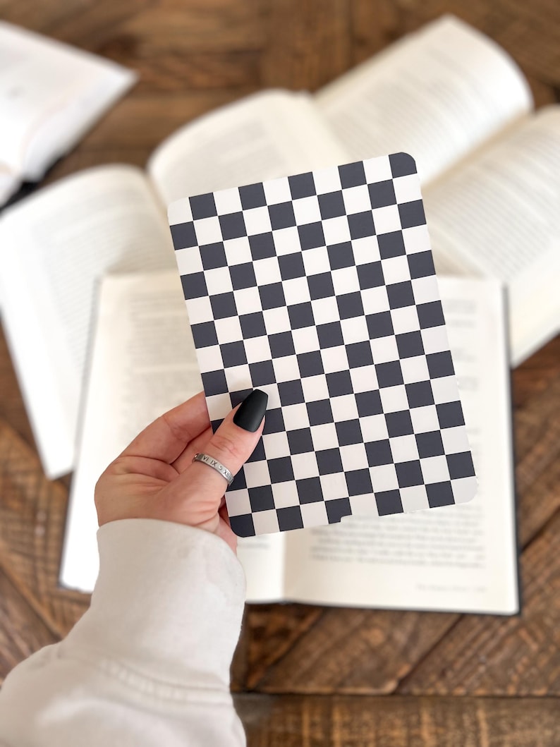 May include: A rectangular card featuring a repeating black and white checkered pattern. The card has rounded corners and a flat surface, displaying a high-contrast grid design consisting of alternating dark and light square tiles across the entire face.