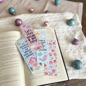 May include: Four pink and blue bookmarks with illustrations of mugs, teacups, and a small house. The bookmarks feature text that reads "Let's stay inside & get cozy", "It's beginning to smell like winter small town romance", "Now is the time for books & calling", and "Little Turkey Shoppe".