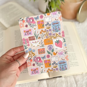 May include: A rectangular postcard featuring a repeating pattern of vintage-style postage stamps with floral and butterfly designs. The stamps include images of flowers, strawberries, and birds, in shades of pink, orange, and blue. The background is a light peach color.