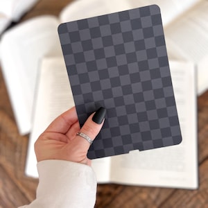 May include: A rectangular card featuring a dark gray and black checkered pattern with rounded corners. The card has a small notch at the bottom center edge and a smooth, matte finish, displaying a consistent grid design across its entire surface.